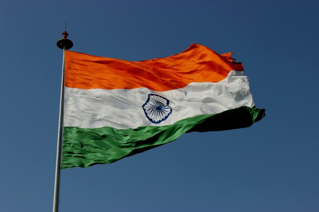 The Indian national flag waves proudly against a clear blue sky, symbolizing unity and pride.